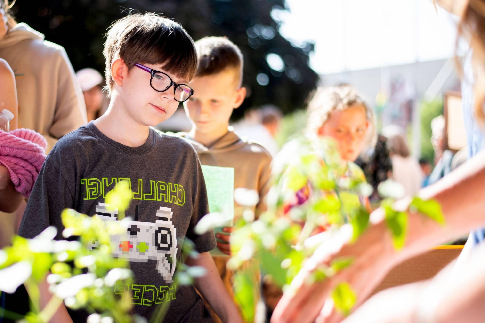 Groundswell Stewardship Initiative student looks at a plant at the Groundswell Student Project Showcase